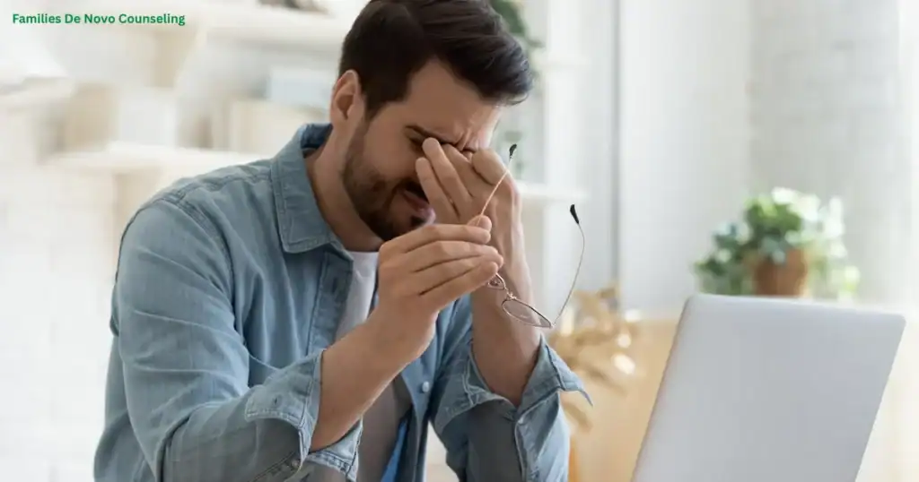 A stressed young man holding his glasses and rubbing his eyes while sitting at a laptop, representing how young adults feel lost due to career pressure, mental health challenges, emotional exhaustion, self-doubt, and uncertainty about the future